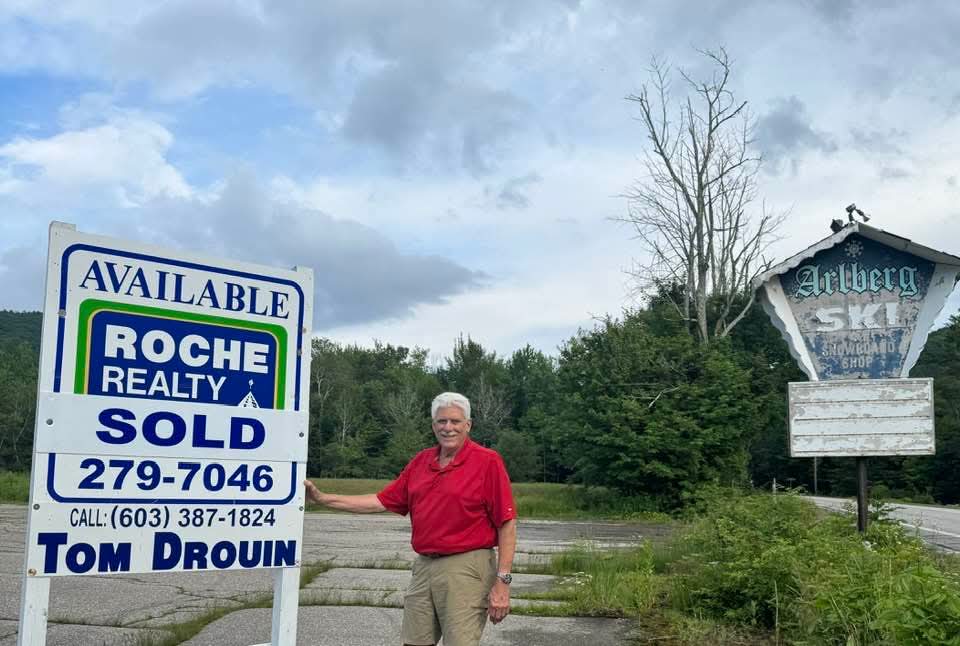 Tom Drouin with sold sign at the historic Arlberg Inn site